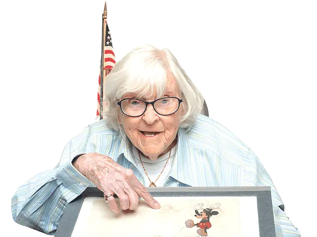 Living An older woman holding up a drawing of mickey mouse.