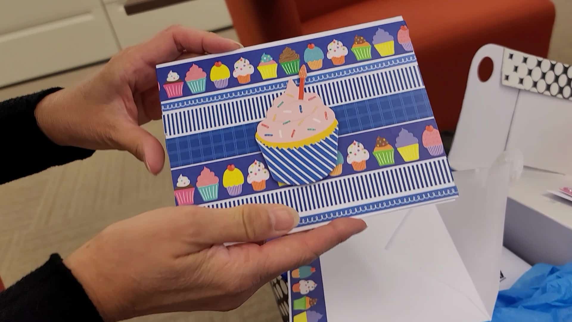 vlcsnap-2023-06-03-11h10m03s122 A person holding a card with a cupcake on it.