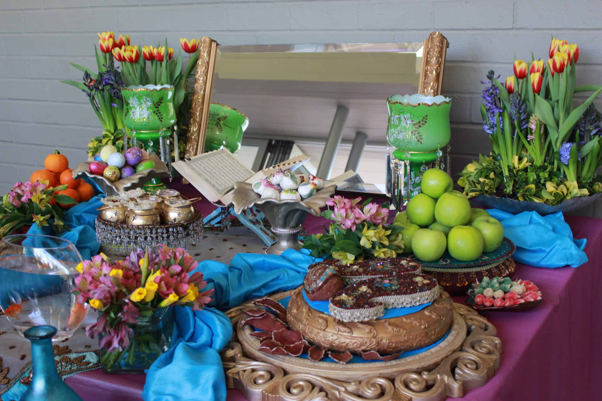 Nowruz Colorful banquet table with an assortment of fruits, cakes, flowers, and decorative objects.